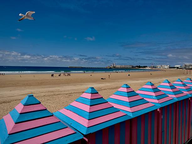 Les Sables d’Olonne, Vendée, France -
June the 23th, 2025 :
Beach and pier of les Sables d’Olonne during summer with cloudy sky